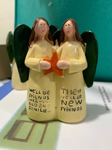 Detailed close-up of resin angel statues with orange star and friendship quote engraving
