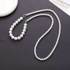 Macro detail of white acrylic bead chain with silver clasp on sleek black background