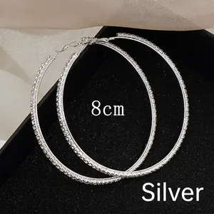 Macro shot of oversized 8cm silver hoop earrings with glittering white rhinestones