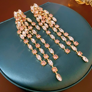 Close-up of elegant long tassel earrings with pink and clear crystals in gold setting