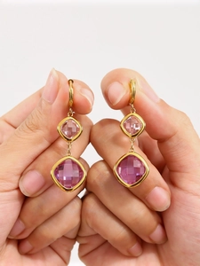 Detailed view of hand-held gold earrings with layered square pink Czech glass stones