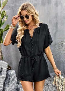 Close-up of black waffle knit romper with V-neck, buttons and drawstring waist detail