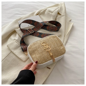 Detail of woven straw handbag with bohemian geometric strap and gold tassel accent