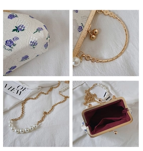 Detail of white lace embroidery shell bag with purple flowers and pearl chain strap
