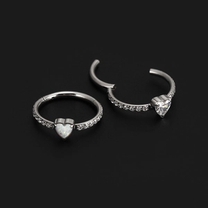 Detail of silver hinge rings with white heart opal and sparkling zircon stones on black background