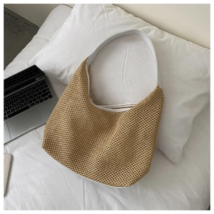 Detail of a khaki woven beach tote bag with white shoulder straps on a clean white bed