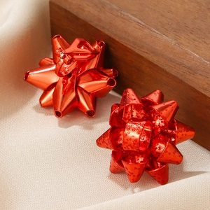 Dettaglio di orecchini a clip con fiocco rosso festivo e glitter su raso e legno