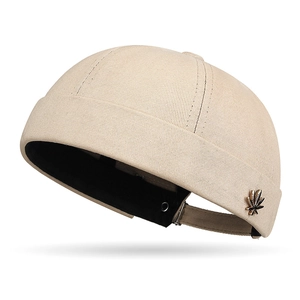 Beige cotton brimless docker hat with maple leaf metal badge and adjustable strap