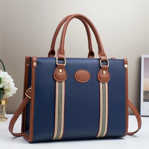 Navy blue faux leather tote bag with brown handles and a central striped webbing detail