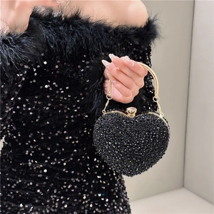 Macro shot of heart-shaped evening bag with black rhinestones and gold ring handle