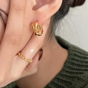 Close-up of minimalist gold-plated knot hoop earrings and bamboo texture open ring