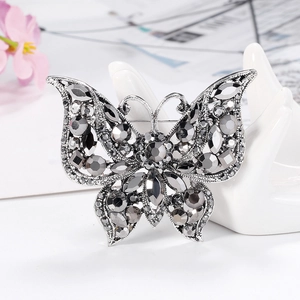 Vintage silver butterfly brooch with dark grey rhinestones on a white hand display
