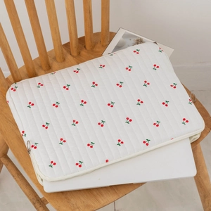 Detailed view of white quilted laptop sleeve with red cherry prints and side zipper