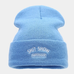 Dettaglio del berretto in maglia azzurro con ricamo bianco SHIT SHOW SUPERVISOR