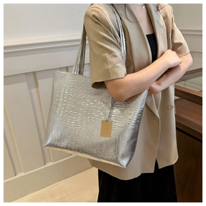 Detailed close-up of silver crocodile embossed tote bag texture with golden tag