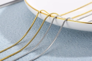 Close-up of golden and silver adjustable snake chain necklaces on a ceramic dish