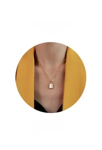 Detail of a minimalist 18k gold plated necklace featuring a white shell pendant on a model