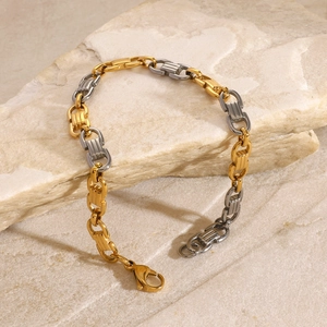 Détail du bracelet chaîne gourmette bicolore or et argent posé sur pierre