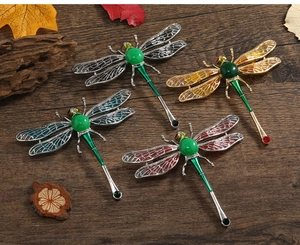 Detailed top view of vintage dragonfly brooches with colorful wings on a rustic wooden base