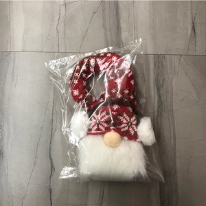 Détail de la peluche gnome de Noël avec bonnet tricoté à flocons en emballage protecteur