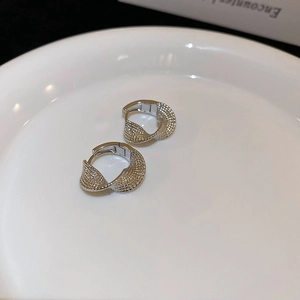Detailed close-up of silver twisted hoop earrings with textured finish on white ceramic