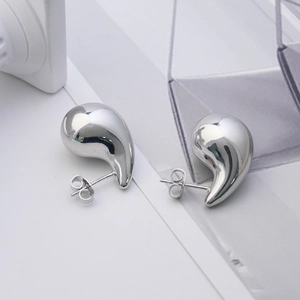 Macro detail of polished silver teardrop stud earrings with secure butterfly backings