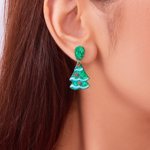 Close-up of green acrylic Christmas tree earrings with glitter and star details on model
