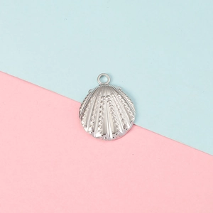 Detailed view of a silver shell pendant with embossed texture on a soft colored background