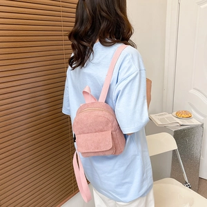Close-up of pink corduroy mini backpack on model's back in a cozy home setting