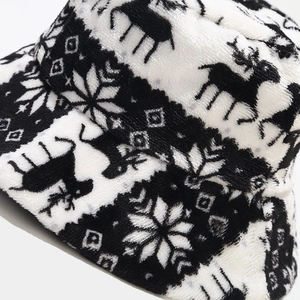 Close-up detail of plush winter bucket hat showing Nordic reindeer and snowflake patterns