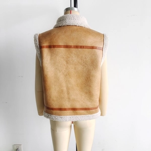 Detail of tan faux leather vest with white shearling trim and brown decorative back straps