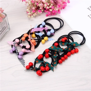 Cute cherry elastic hair ties with colorful beads and plaid bows on a wood table