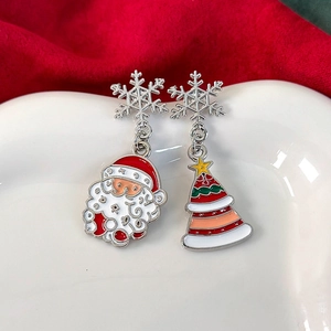 Nahaufnahme asymmetrischer Weihnachtsohrringe mit Weihnachtsmann- und Baumanhängern