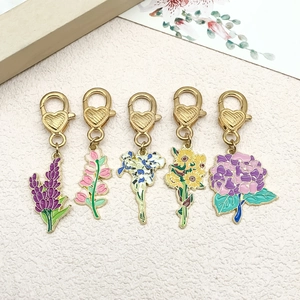 Detail of five colorful enamel flower charms with golden heart clasps and floral card