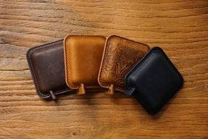 Top view of four vintage leather mini tape measures in different colors on wooden surface