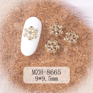 Macro detail of snowflake nail charms with gold metal base and rhinestones, size 9x9.5mm