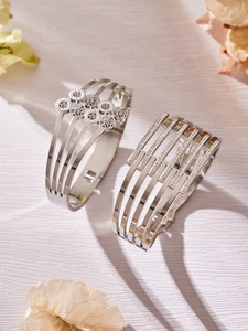 Dettaglio di bracciali multistrato in argento con fiori traforati e strass scintillanti