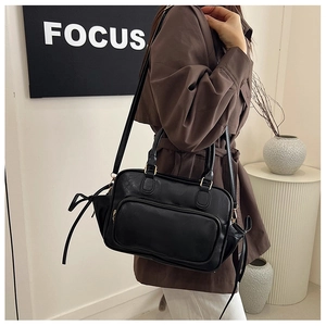 Chic black leather handbag with side bow details and golden hardware on a model