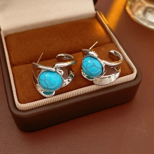 Detail of vintage silver earrings with blue turquoise stones inside a jewelry box
