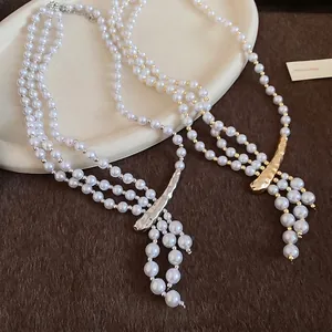 Multilayer pearl necklace with irregular hammered metal pendant on ceramic tray