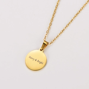 Close-up of golden stainless steel round pendant with Merry & Bright engraved text