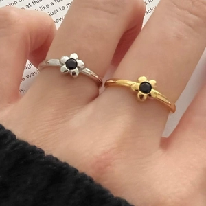 Detailed view of minimalist S925 silver flower rings in gold and silver finish with black stone