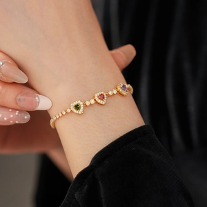 Detail of 18k gold plated heart bracelet featuring red, green and purple faceted gemstones