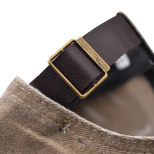 Detailed macro of vintage bronze buckle and brown leather strap on cotton baseball cap