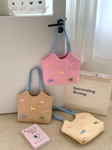 Detail of corduroy tote bags with colorful knitted bows and soft blue ribbon handles