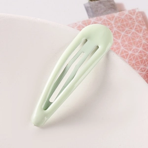 Close-up of a mint green water-drop hair clip with glossy finish on a display tray
