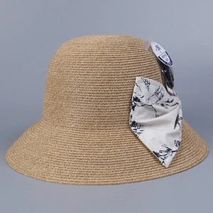 Detail of light brown woven straw hat featuring a floral bow and UPF 50+ sun protection tag