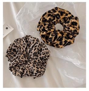 Detail of two leopard print scrunchies with different patterns on white textured fabric