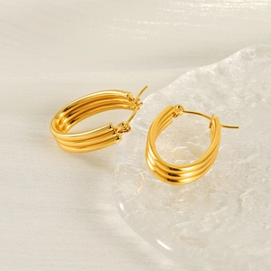 Minimalist triple-layer oval hoop earrings in gold finish on a glass tray