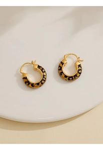 Detail of 14k gold-plated hoop earrings with a vintage leopard print pattern on white tray